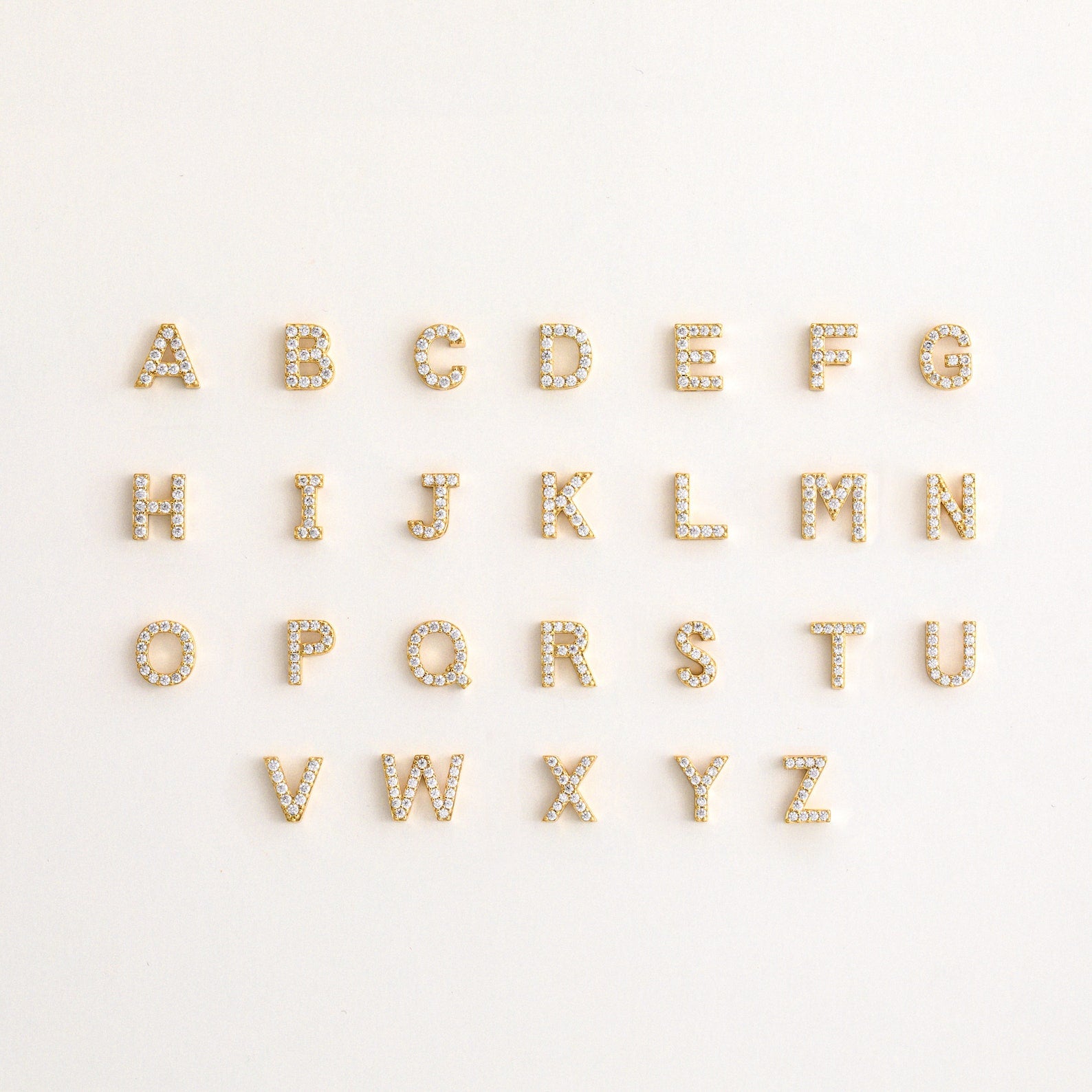 A set of letters on a white background, inspired by the Pave Initial Huggies—ideal for gifting someone a personalized touch.