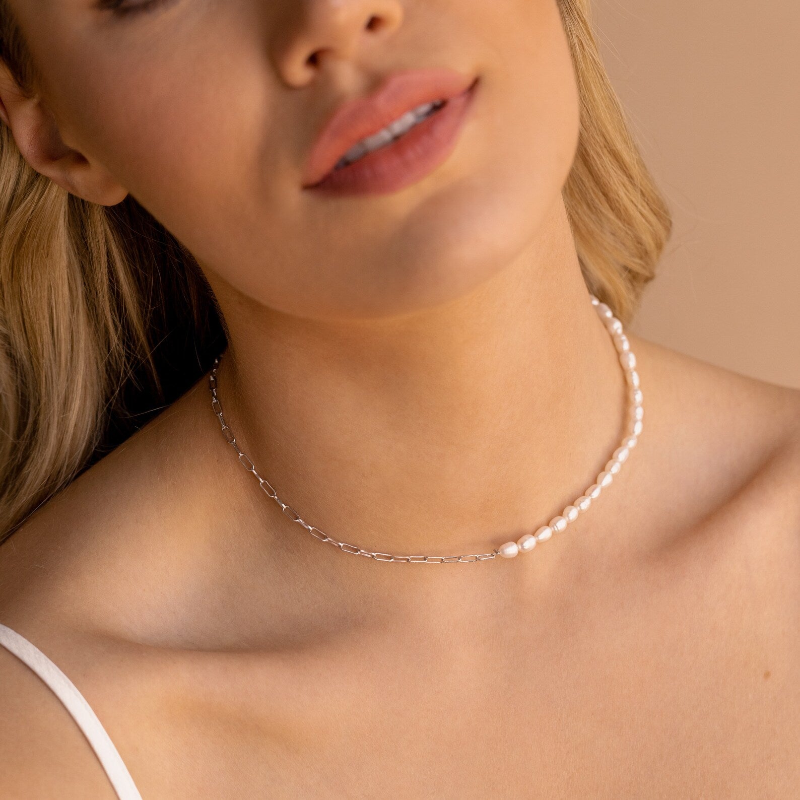 A woman wears the Pearl & Paperclip Chain Necklace, shown in a close-up of her neck and lower face.