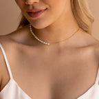 A woman wears the Pearl & Paperclip Chain Necklace, a two-tone choker featuring pearls and gold links, styled with a white spaghetti strap top.