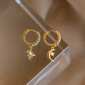 Astra Moon & Star Huggies: Gold hoops featuring a star on one earring and a moon on the other, each set with opal accents, bring celestial charm and radiant shine to any outfit.