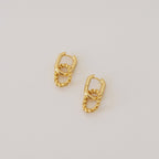 Kenzie Chain Link Earrings feature a twisted gold design for an edgy look, shown against a simple light background.