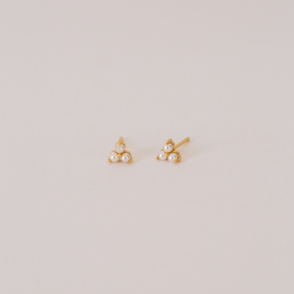 The Maud Pearl Studs are elegant gold earrings featuring three petite pearls in a triangle design—a timeless, luxurious gift for any occasion, shown simply on a light background.