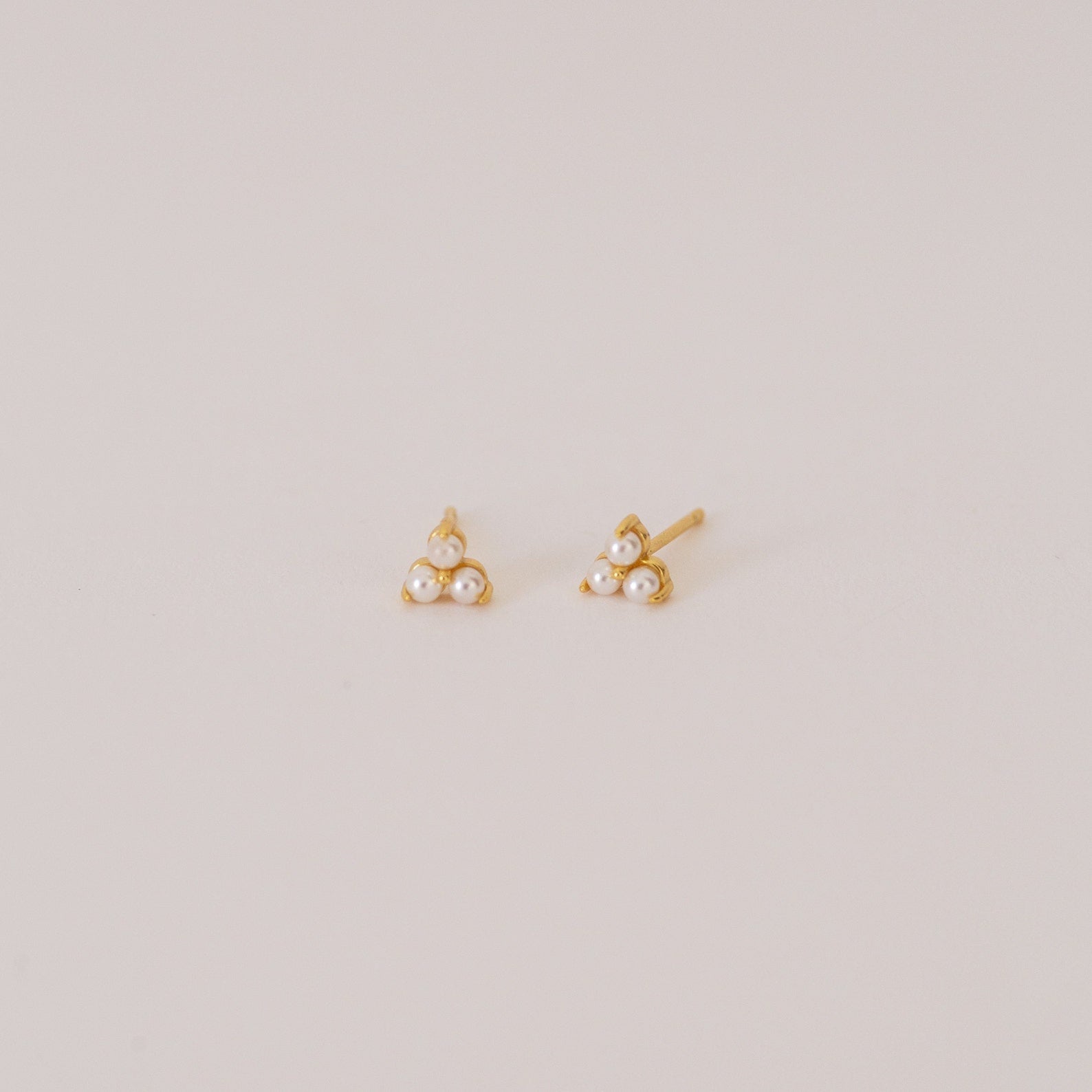 The Maud Pearl Studs are elegant gold earrings featuring three petite pearls in a triangle design—a timeless, luxurious gift for any occasion, shown simply on a light background.
