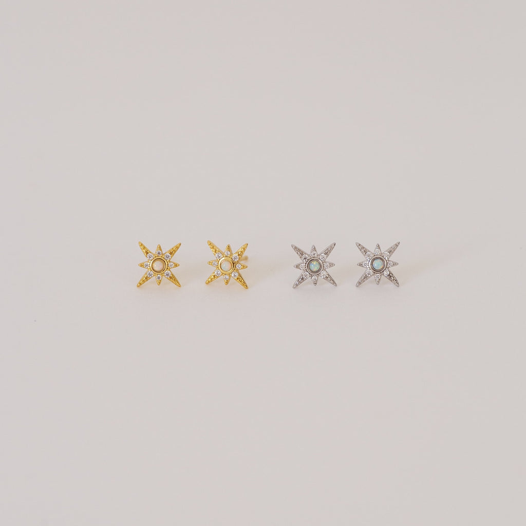 Two pairs of Starburst Studs—one gold, one silver—each adorned with a small central gem, reminiscent of diamond earrings, shown on a plain background.