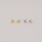 Two pairs of Starburst Studs—one gold, one silver—each adorned with a small central gem, reminiscent of diamond earrings, shown on a plain background.