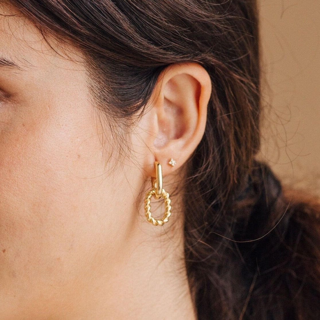 Close-up of a woman's ear wearing Kenzie Chain Link Earrings—large gold hoops with a twisted design, ideal for those who love statement earrings and bold, edgy jewelry.