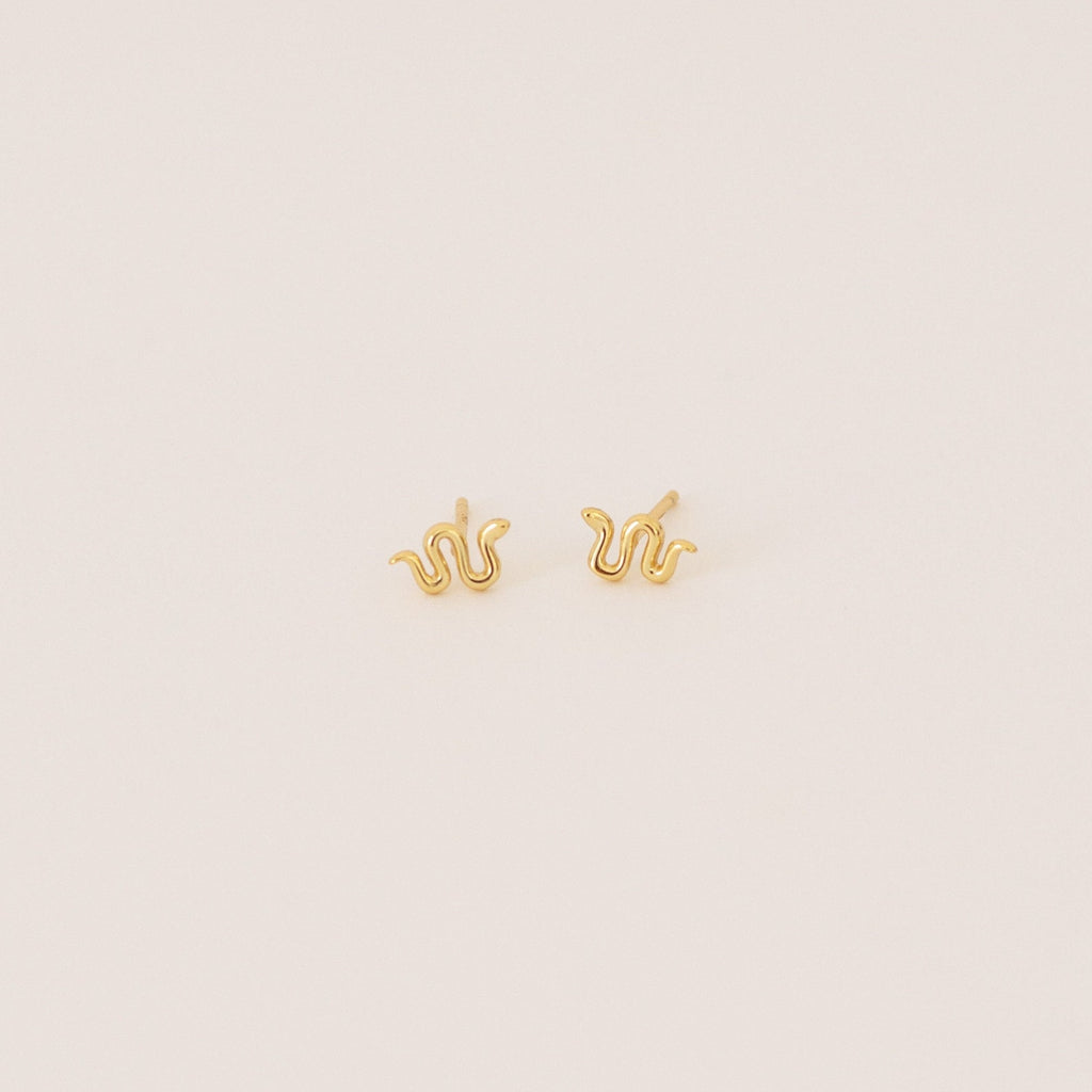 Tiny Python Studs: Small gold snake-shaped earrings that bring a boho-luxe accent to any outfit. Featured on a minimalist light background.