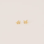 Tiny Python Studs: Small gold snake-shaped earrings that bring a boho-luxe accent to any outfit. Featured on a minimalist light background.
