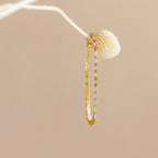 The Claudia Baguette Tennis Bracelet draped gracefully on a white branch with a textured cream bud, capturing the refined allure of elegant jewelry.