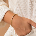 A person in a white pleated blouse wears the elegant Claudia Baguette Tennis Bracelet and has their hand in their pocket.