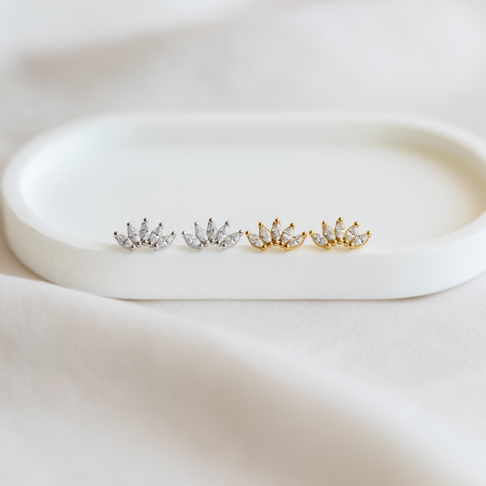 Two pairs of lotus-shaped floral earrings, one silver and one gold, displayed on a white tray. Perfect as a bridal gift or for pairing with Odessa Marquise Studs to add an elegant touch.