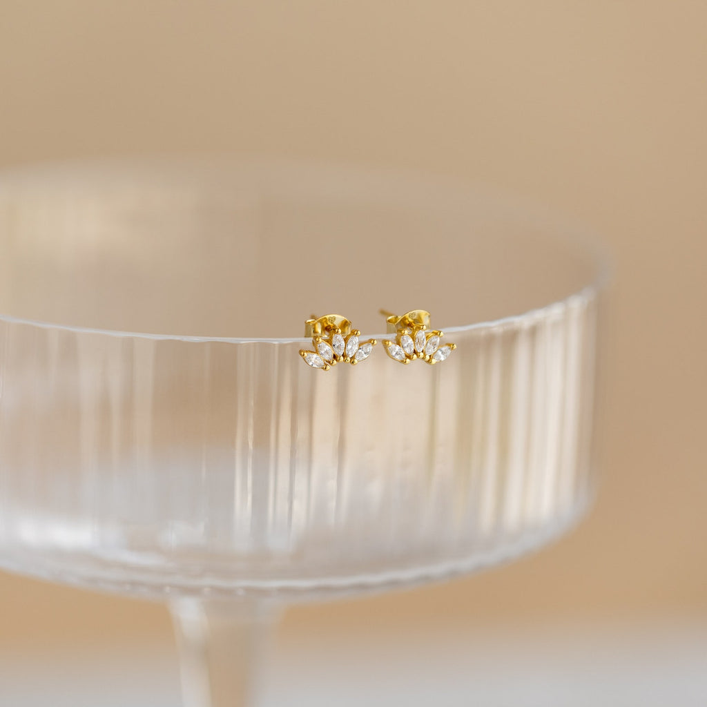 Odessa Marquise Studs, displayed on the rim of a clear, ribbed glass cup—an elegant bridal gift choice.