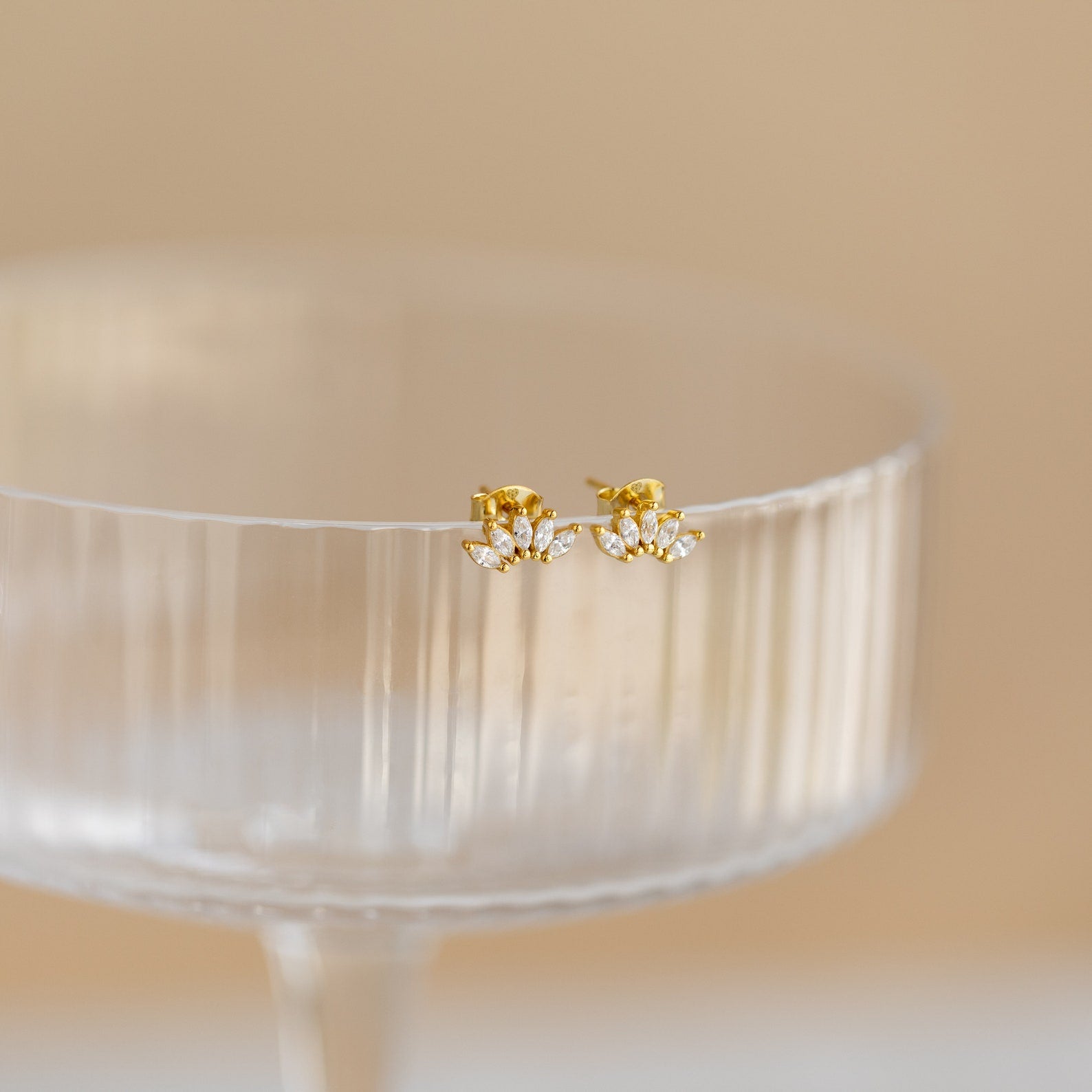 Odessa Marquise Studs, displayed on the rim of a clear, ribbed glass cup—an elegant bridal gift choice.