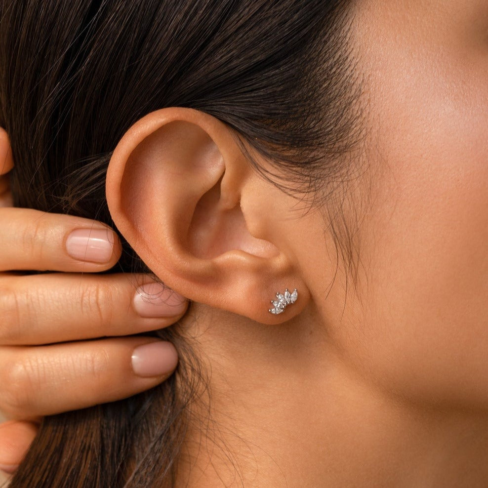 Close-up of a woman's ear wearing the elegant Odessa Marquise Studs and a small silver crystal ear cuff; her hand rests near her ear.