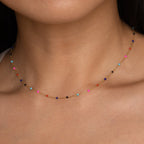 Close-up of a woman wearing the Rainbow Station Necklace, a delicate gold piece with small, colorful beads—perfect for adding a subtle touch to any look.