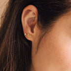 A close-up of a woman's ear wearing Tiny Python Studs for an elegant, dainty jewelry accent.
