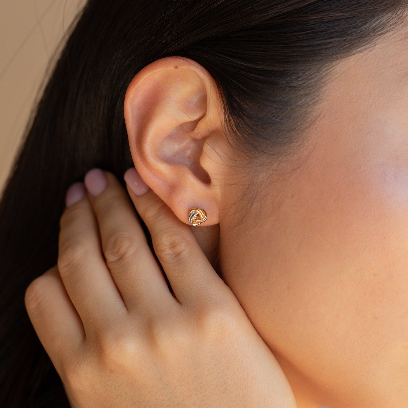 Close-up of a woman’s ear adorned with Trinity Knot Studs; her hand gently rests nearby—an elegant choice for an anniversary gift.