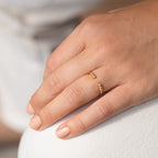 A hand with natural nails wears the Serafina Diamond Ring in dainty style, featuring small diamonds on the ring finger.