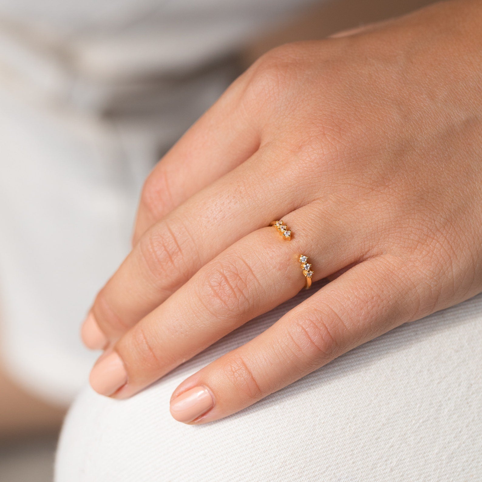 A hand with natural nails wears the Serafina Diamond Ring in dainty style, featuring small diamonds on the ring finger.