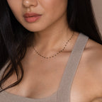 Woman wearing a Black Station Necklace and a beige textured tank top, with long dark hair—a chic nod to the latest fashion trend.