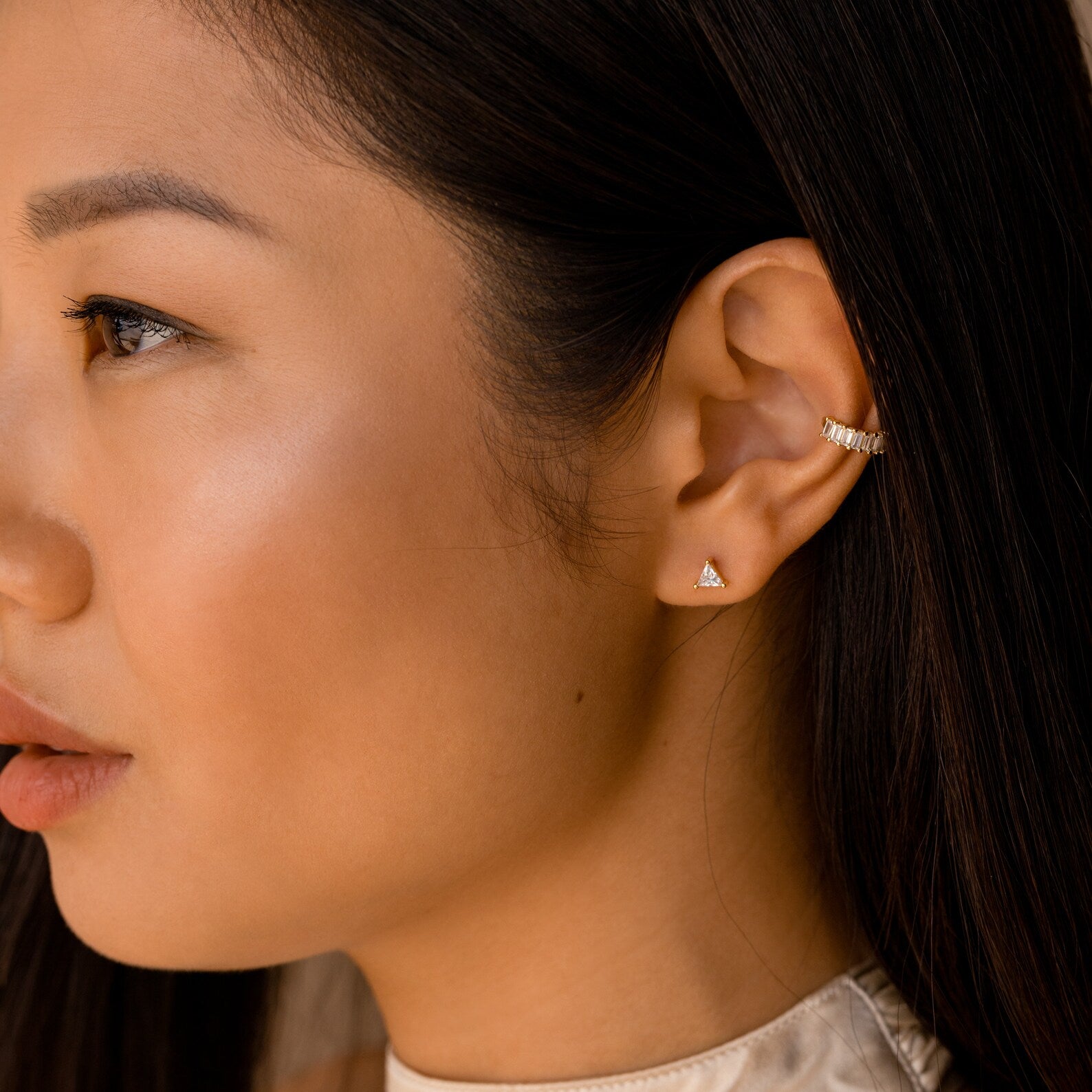 A woman with long dark hair wears modern classic jewelry—a gold ear cuff paired with Trixie Diamond Studs on her left ear.