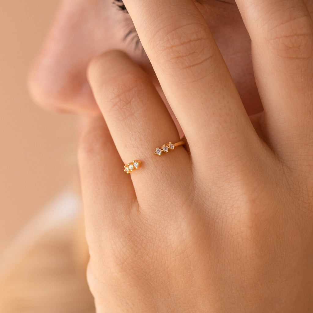 A hand adorned with the Serafina Diamond Ring, featuring a delicate and dainty floral design in gold, posed gently near the lips and cheek.