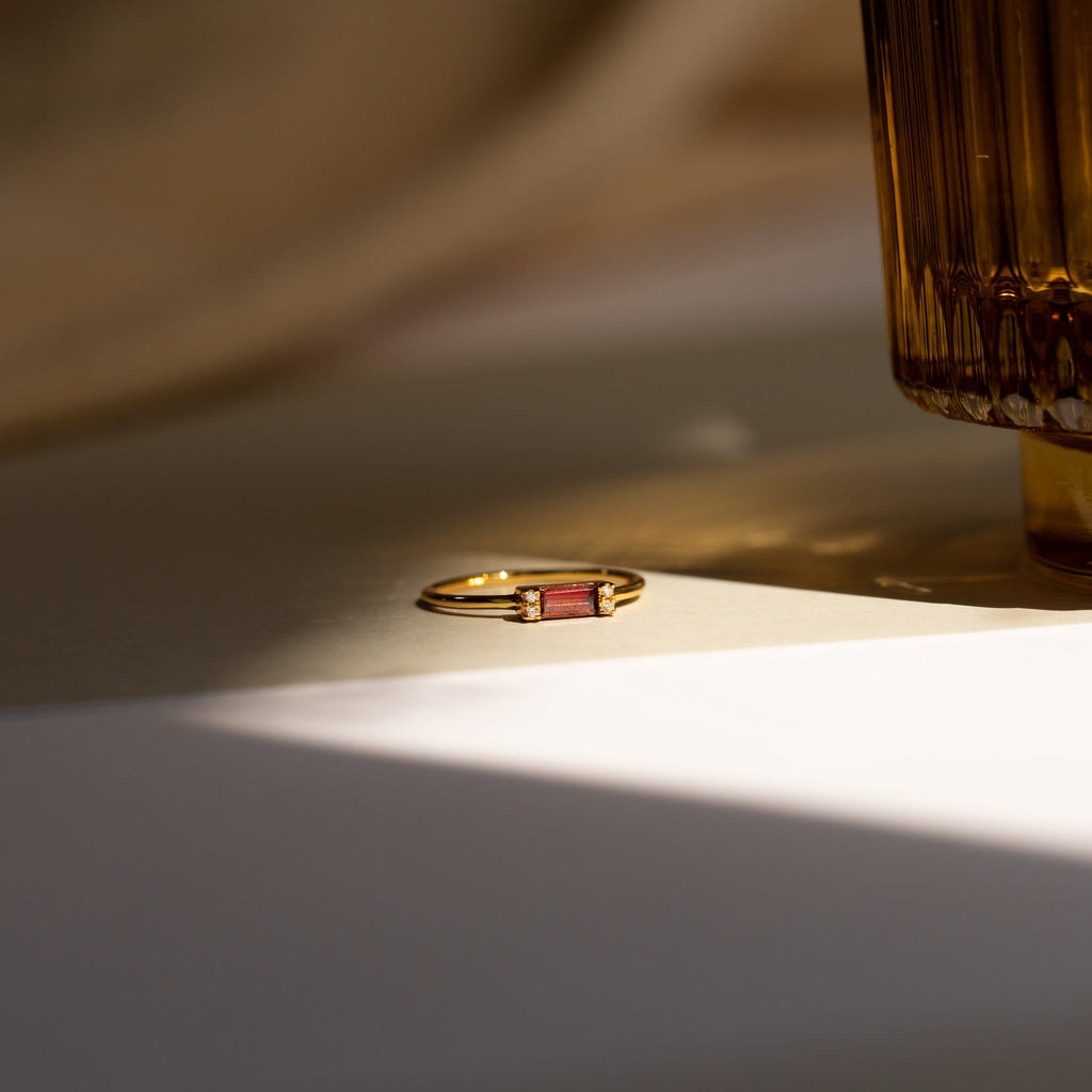 The Empire Garnet Ring, featuring a gold band, rests elegantly on the table.