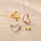 Three heart-shaped Custom Bead Heart Necklaces in gold, rose gold, and silver, each with personalized engraved beads, are displayed on a beige surface. Add the perfect custom necklace to your collection today.