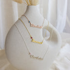 Three Mellow Birthstone Name Necklaces (“Elizabeth,” “Summer,” and “Charlotte”) are displayed on a white ceramic vase, highlighting the elegance of customizable minimalist jewelry—each one made to order for a unique touch.