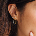 Close-up of a woman's ear wearing the Florence Diamond Chain Earrings—gold and silver chains link two studs, accented with subtle crystals for extra sparkle.