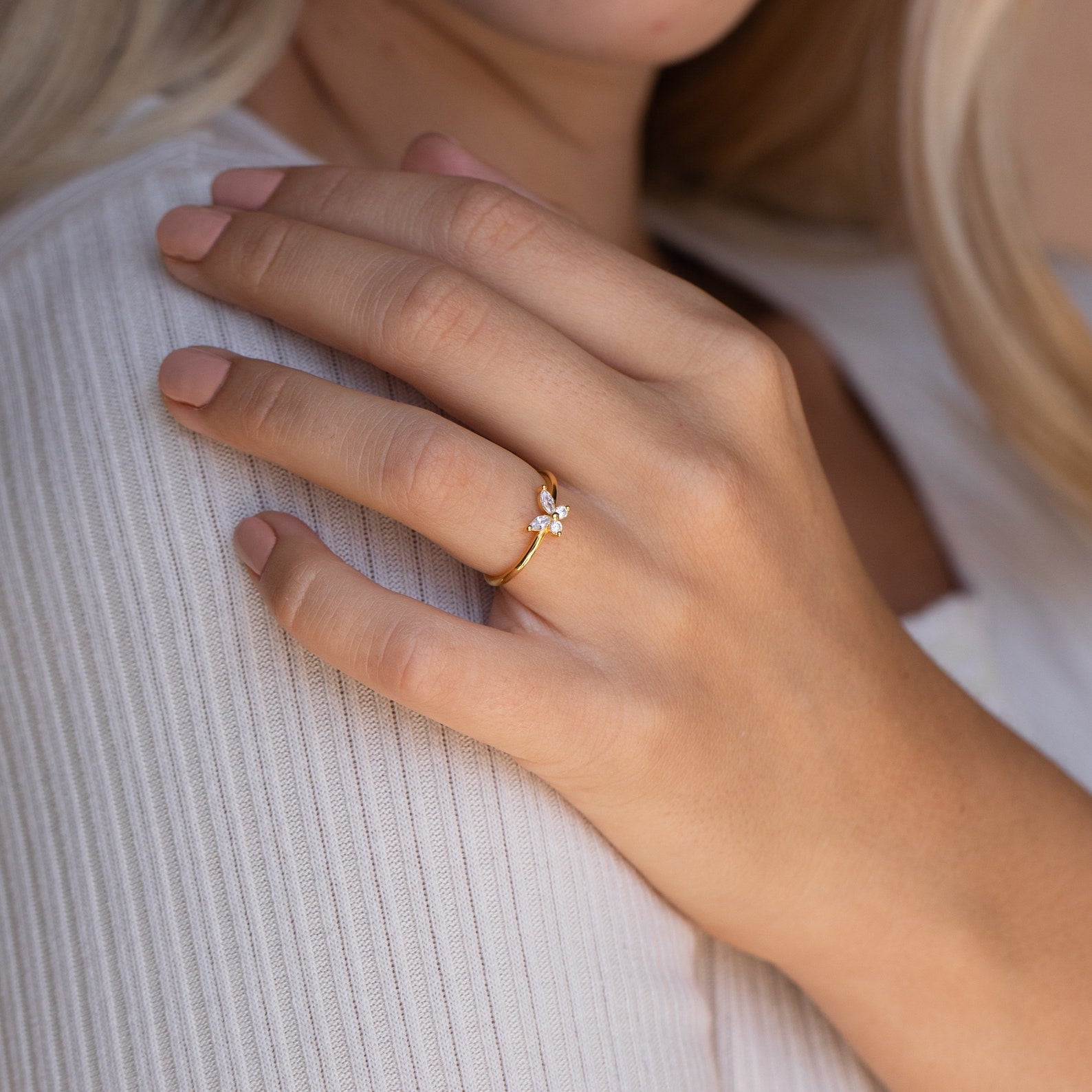 A hand wearing the Mariposa Diamond Ring rests on a ribbed white top, the sparkling stone adding a delicate touch.