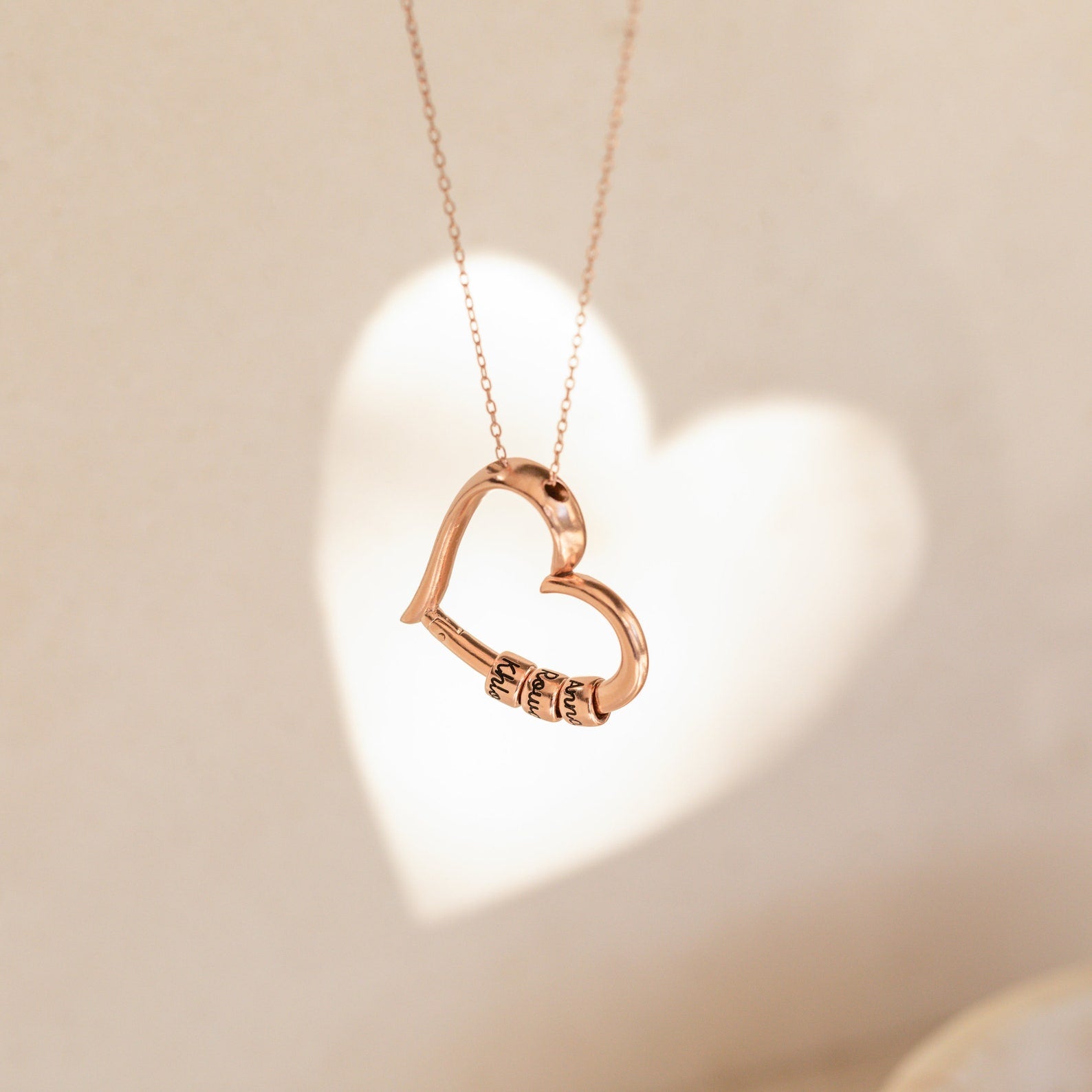 Rose gold heart pendant casting a shadow on a light background, perfect for the Custom Bead Heart Necklace.