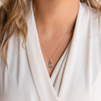A woman wearing the Tear Drop Fingerprint Necklace with a white V-neck blouse.