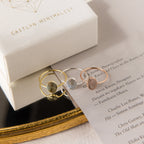 The Fingerprint Oval Ring, a handcrafted minimalist piece in gold, silver, and rose gold, is displayed on a card beside a branded jewelry box.