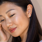 Woman with long dark hair wearing pastel enamel Unicorn Studs earrings, smiling gently—a charming gift for girls.