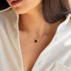 A woman in a white shirt wears the Waverly Black Necklace, a gold satellite chain adorned with a small black enamel pendant.