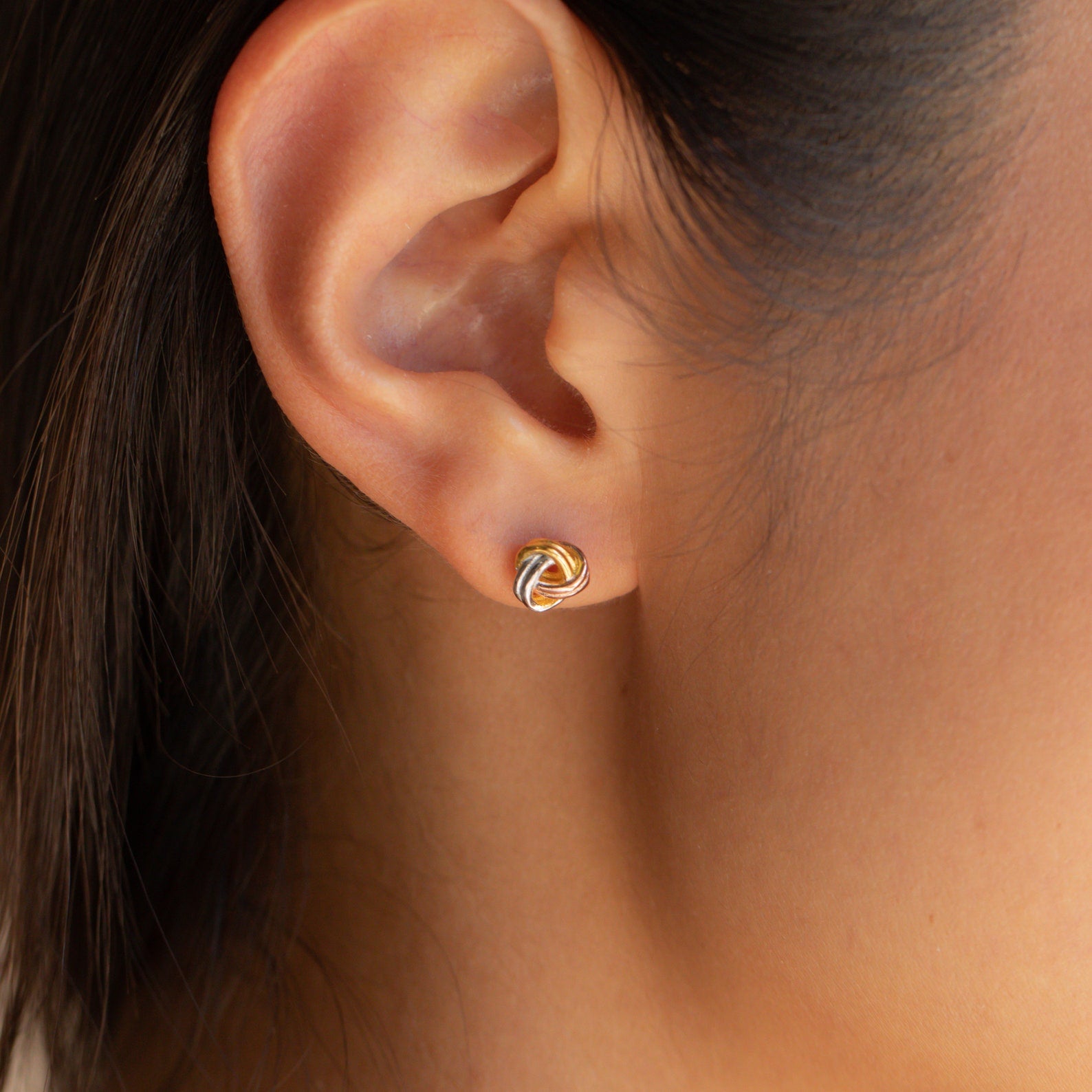Close-up of an ear wearing a Trinity Knot Stud—an elegant gold earring perfect for everyday wear or as a thoughtful anniversary gift.