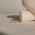 Trinity Knot Studs displayed on a light beige surface with textured ceramic accents—an ideal, thoughtful anniversary gift.