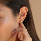 A person touching a Trinity Knot Stud earring worn on their ear.