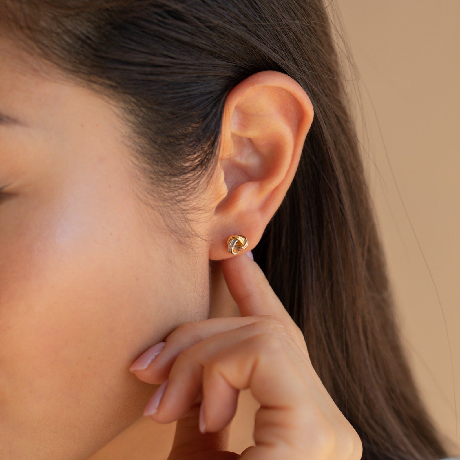 A person touching a Trinity Knot Stud earring worn on their ear.