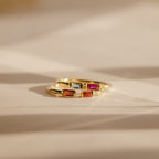 Two Duo Baguette Birthstone Rings with rectangular red, orange, and clear stones rest on a soft beige surface—an elegant personalized gift from the Duo Baguette Birthstone Ring collection.