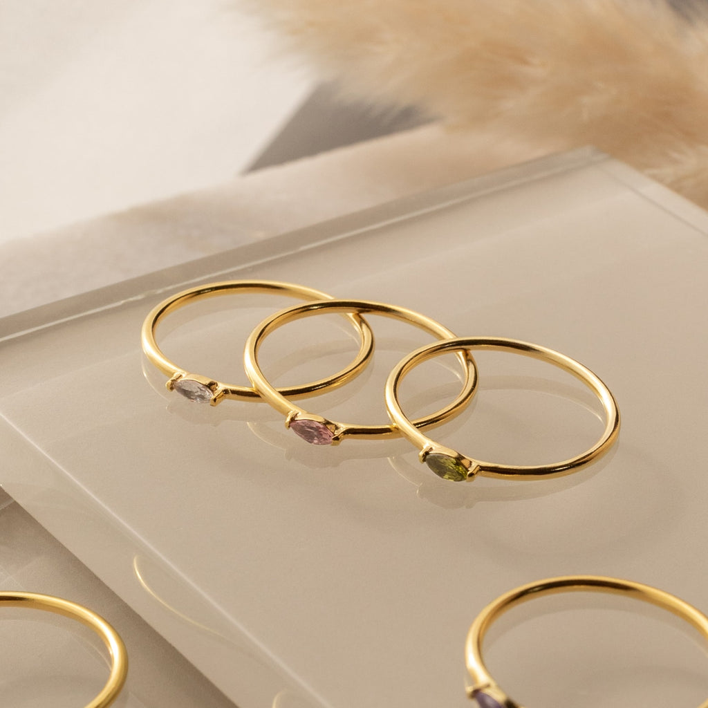 The Marquise Birthstone Ring features a gold band with a marquise-cut gemstone, perfect for stacking or wearing alone as a personalized accessory.
