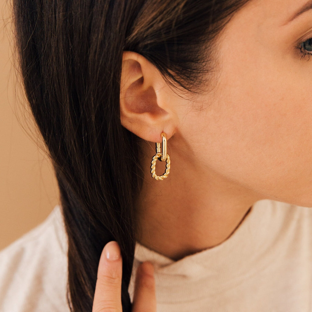 Woman wearing the Kenzie Chain Link Earrings, touching her brown hair, shown from the side—an effortlessly chic take on statement earrings.