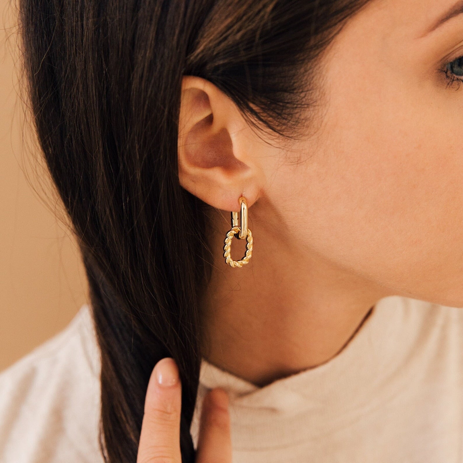 Woman wearing the Kenzie Chain Link Earrings, touching her brown hair, shown from the side—an effortlessly chic take on statement earrings.