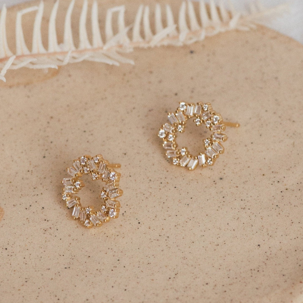 Reina Cluster Studs: Gold circular studs adorned with small clear crystals, displayed on a neutral speckled surface—ideal as timeless bridal earrings for your wedding jewelry collection.