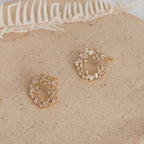 Reina Cluster Studs: Gold circular studs adorned with small clear crystals, displayed on a neutral speckled surface—ideal as timeless bridal earrings for your wedding jewelry collection.