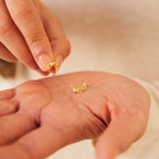 A hand holds a small gold hoop diamond pearl earring, while another hand picks up the matching Eclipse Moon Stud earring.