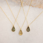 Three Tear Drop Fingerprint Necklaces rest on a light surface—two with fingerprint keepsakes and one engraved “Mom”—creating a meaningful personalized amulet collection.