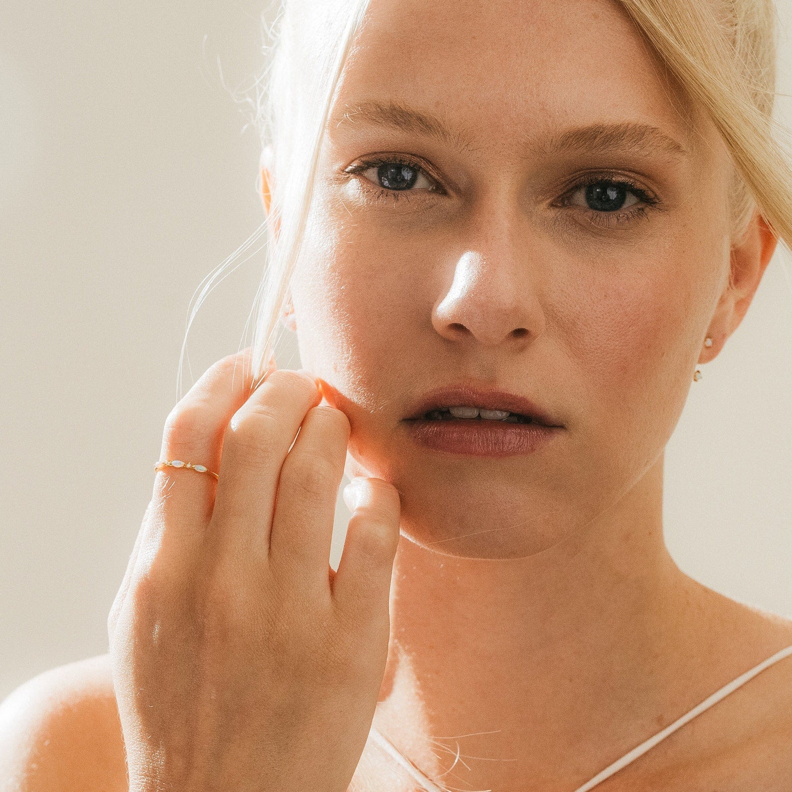 Portrait of a woman with blonde hair wearing the Alessia Trio Opal Ring, highlighting its delicate opal and gemstone details.