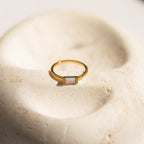 The Kiera Opal Baguette Ring features a rectangular opal stone set on a smooth band, making it an elegant choice for a promise ring or any special occasion.